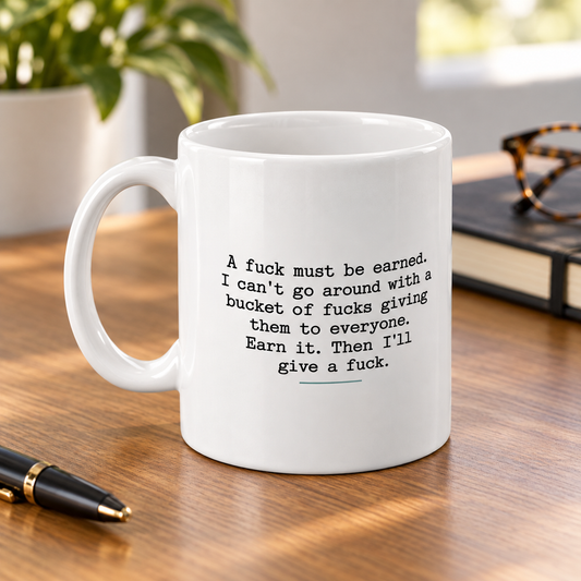 A Fuck Must Be Earned Funny Mug in a styled lifestyle setting