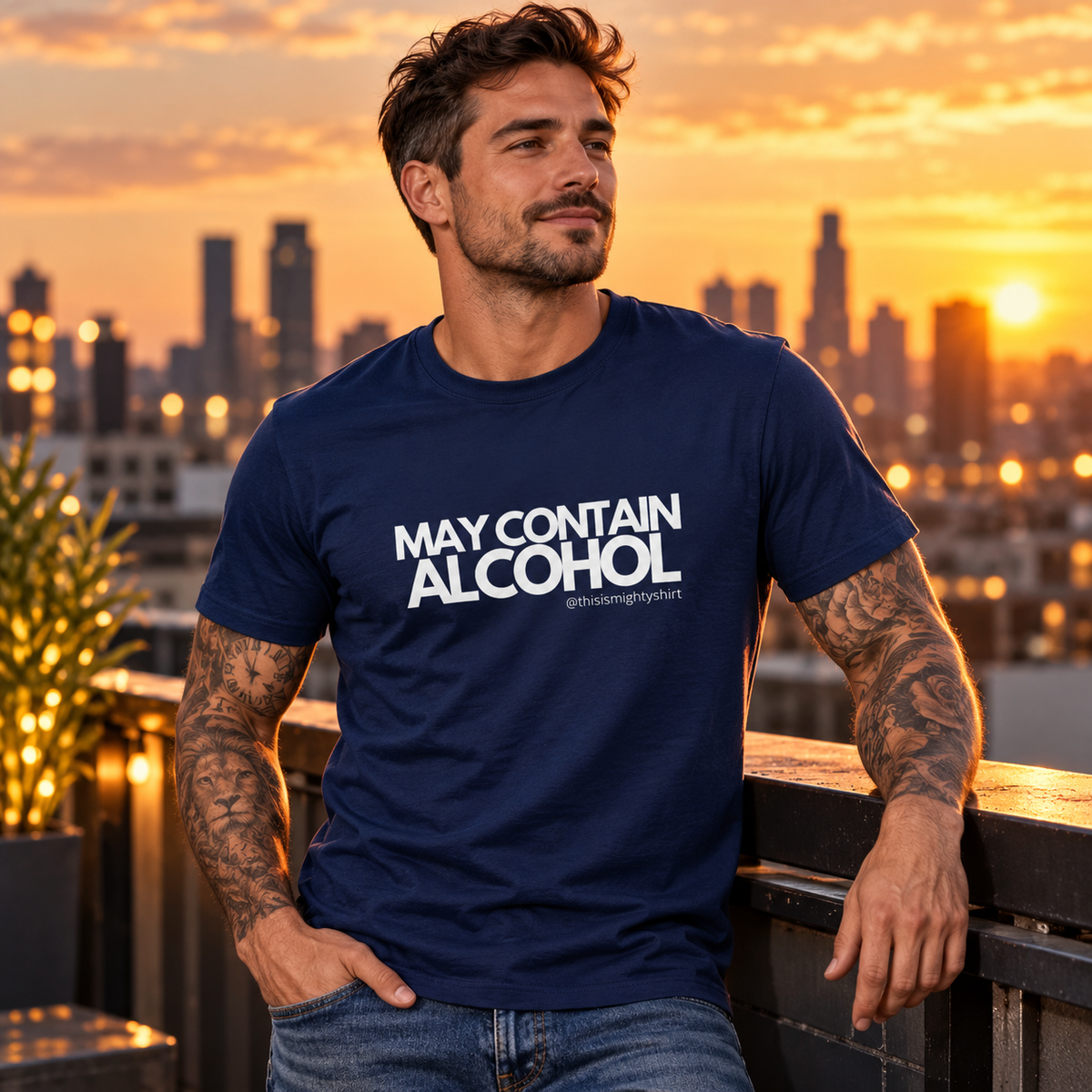 Tattooed man wearing navy May Contain Alcohol T-shirt on a rooftop at sunset