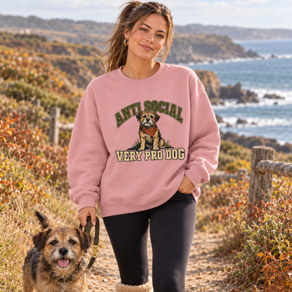 Woman in the Dusty Pink Anti Social Very Pro Dog sweatshirt walking a terrier along the coast
