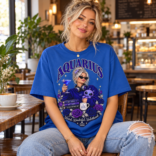 Aquarius Weird Wonderful Unbothered Women's T-Shirt – Dark Colours, model wearing the original design in a cosy stylish coffee shop indoors.