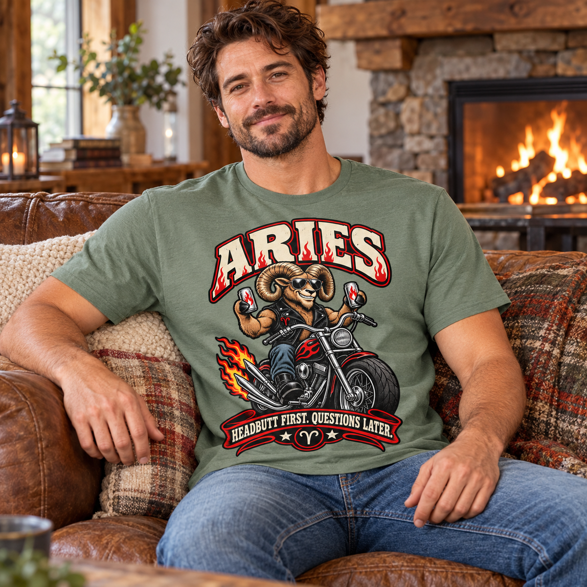 Aries Headbutt First Questions Later Men's T-Shirt, model wearing the original design in a seated comfortably on a cottage sofa beside a fireplace indoors.