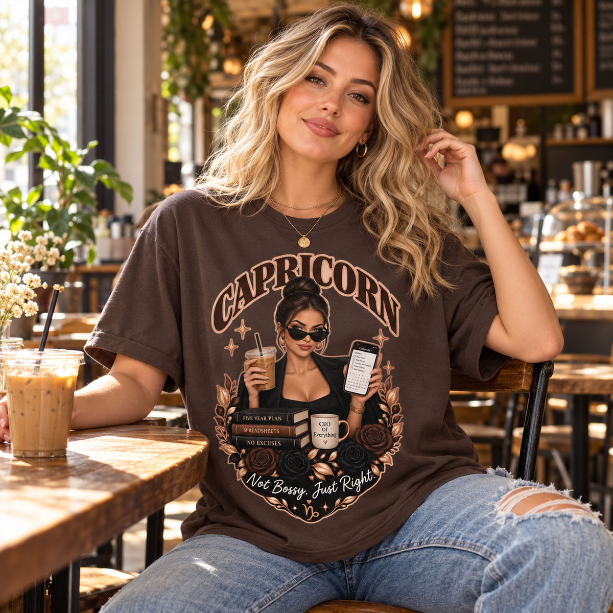 Capricorn Not Bossy Just Right Women's T-Shirt – Dark in Dark Chocolate, model inside a stylish warm coffee shop with window light