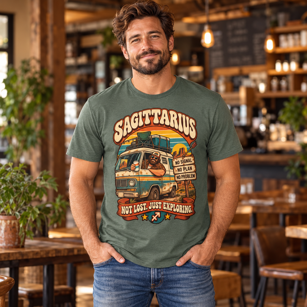 Sagittarius Not Lost Just Exploring Men's T-Shirt in Heather Military Green, model indoors in a warm rustic cafe