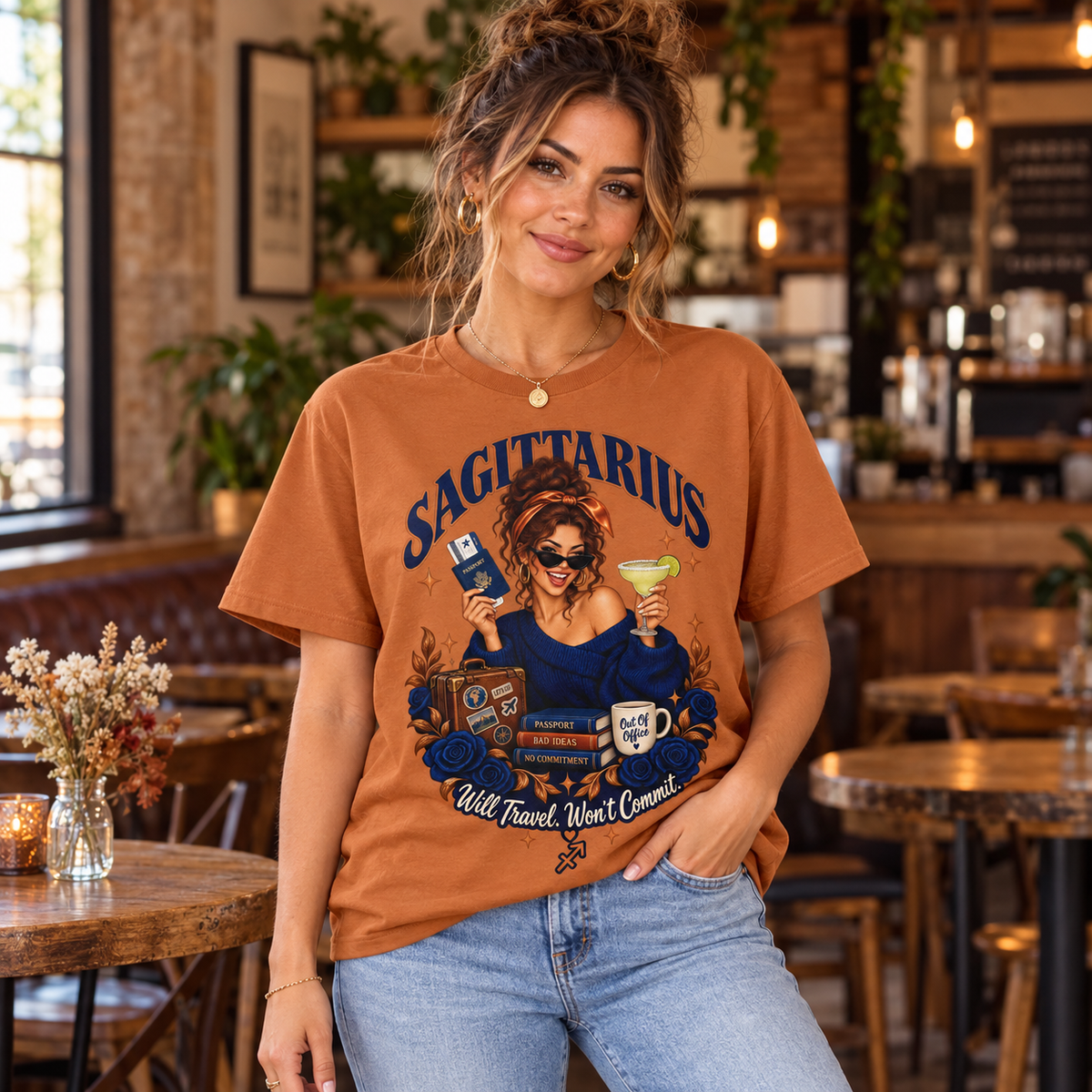 Sagittarius Will Travel Won't Commit Women's T-Shirt – Dark in Fan Texas Orange, model indoors in a warm rustic cafe