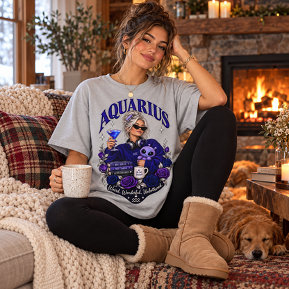 Aquarius Weird Wonderful Unbothered Women's T-Shirt – Dark Colours, model wearing the original design in a seated comfortably on a cottage sofa beside a fireplace indoors.