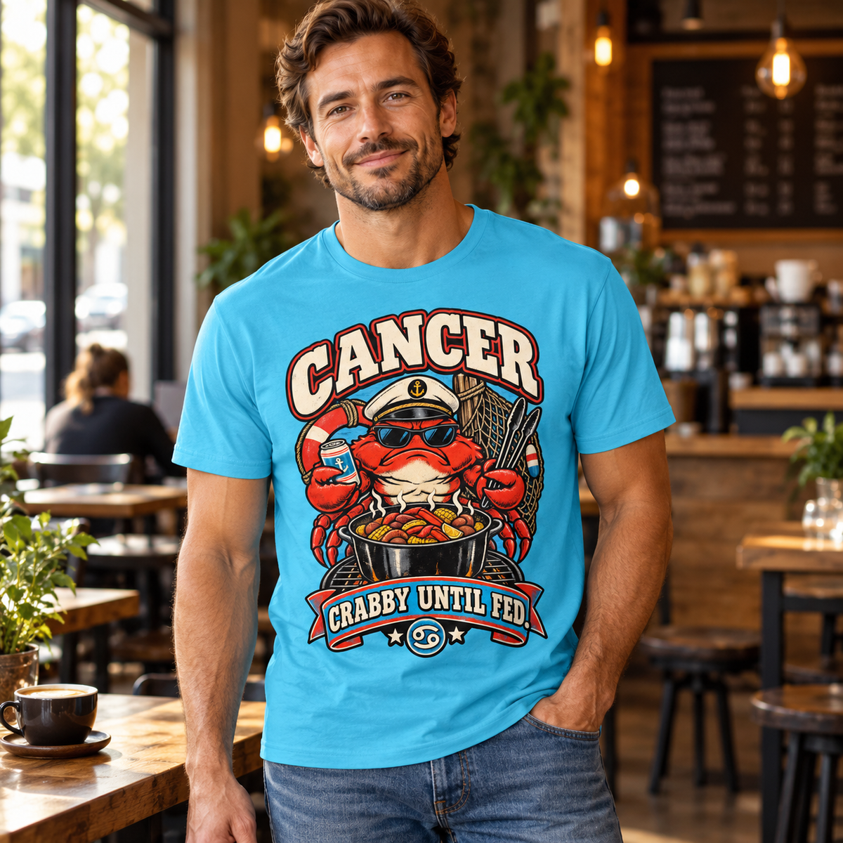 Cancer Crabby Until Fed Men's T-Shirt in Tropical Blue, model inside a stylish warm coffee shop with window light